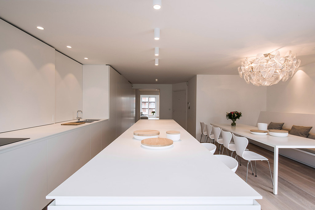 Wit keukenblok, keukeneiland, lange rechthoekige tafel en 6 eetkamer stoelen