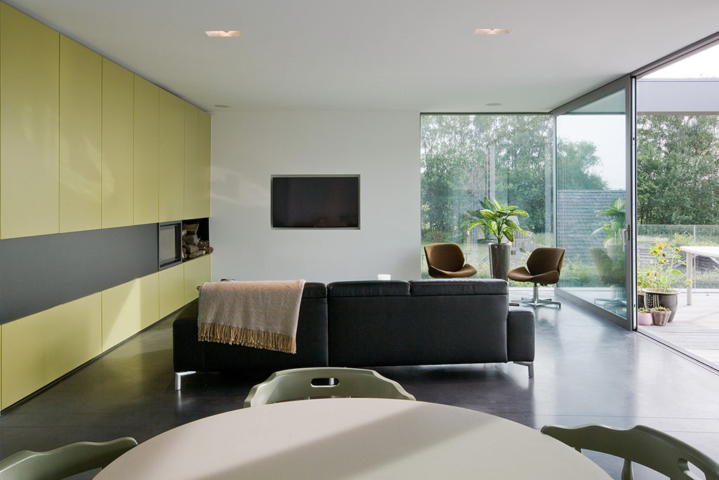 vooraanzicht van een ruime woonkamer met olijfkleurige muur